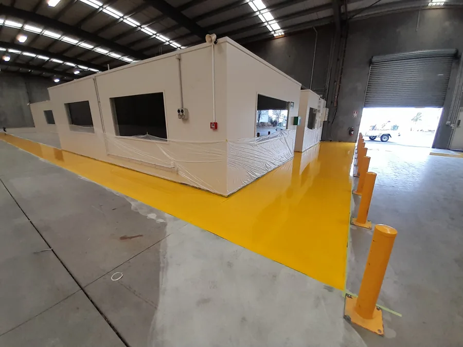Yellow floor zone markings with bollards inside industrial warehouse